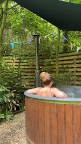A promotional video showcasing a unique Airstream accommodation in a forest setting, highlighting amenities like a private tiki bar, hot tub, cinema room, and riverside location.
