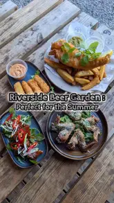 A promotional reel for 'The Moorings', a riverside pub and kitchen. The video features a montage of the venue's exterior, interior, beer garden, and riverside seating pods, interspersed with close-up shots of various dishes including fish and chips, chicken wings, halloumi sticks, pork belly, and desserts.