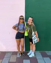 A lifestyle photograph of two friends posing in front of a split-colour pink and green wall at the Barras Market, capturing a casual day out.