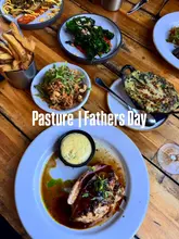 A top-down, flat-lay photograph of a table spread at a restaurant, featuring a main chicken dish, beef fat chips, and various vegetable sides. The image is overlaid with text indicating the venue and occasion.