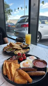 A promotional reel for a new cafe in Blackburn, showcasing a variety of breakfast options including a traditional English breakfast, a Desi breakfast, and French toast, alongside Indian street food snacks like samosas.