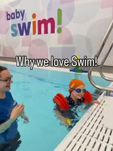 A promotional image for a children's swimming lesson venue, featuring a child in the pool with an instructor. The image uses a bright, clean aesthetic typical of indoor leisure facilities.