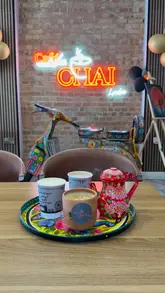 A montage of various food and drink items served at Cafe Chai, including parathas, burgers, and specialty chais, interspersed with shots of the cafe's interior decor.