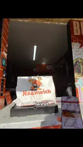 Two creators film a promotional video for a takeaway spot called Naanwich Club in Manchester. They demonstrate using the Sumo Eats app to order a butter chicken pizza for £8.99, walk to the venue to collect it, and then eat it in the car park.