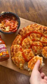 A short, polished video showcasing a Chicago Town pull-apart pizza being dipped into a buffalo sauce. The video focuses on the cheese pull and the dipping action.