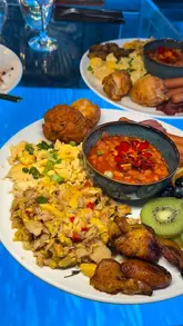 A review of a Caribbean breakfast spot in South East London, featuring a couple trying various dishes including a Caribbean breakfast platter, French toast, and waffles, alongside colourful slushie drinks. The video highlights the venue's interior and menu offerings.
