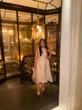 A portrait of a woman posing in a dress inside the opulent, gold-mirrored interior of The Ritz London, likely for an afternoon tea experience.