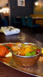 A montage-style promotional video for Dhamroo, an Indian restaurant in Oxford, showcasing various dishes, drinks, and the restaurant's interior decor.