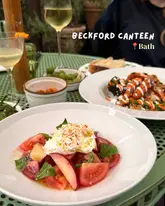 A high-quality, well-lit food photography shot capturing a spread of dishes including burrata and roasted carrots at an outdoor table setting.
