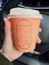 A simple, casual shot of a branded takeaway coffee cup held inside a car.