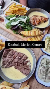 The video features a creator visiting Estabulo to try their new Cafe de Brazil menu. It includes shots of the restaurant interior, the steak and chicken dishes with a buttery sauce, sides like mac and cheese and mushrooms, and a cocktail. The creator provides a voiceover review of the experience.