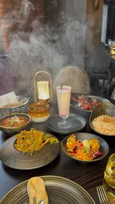 A review of Tyga in Manchester, showcasing modern Indian cuisine. The video features theatrical food presentations, including a smoke dome, and highlights dishes like lamb chops, king prawns with mango salsa, clay pot lamb, and chicken tikka masala. The creator provides commentary on the food quality and the restaurant's atmosphere.