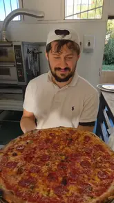 A video showcasing the preparation of a large pepperoni pizza, from stretching the dough to adding toppings, baking, and slicing. The video focuses entirely on the culinary process in a kitchen setting.