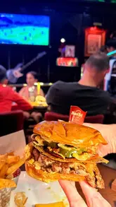 A creator visits the Hard Rock Cafe in London to experience a World Cup watch party. The video features shots of the venue's 'The Back Room', the football match on screens, the crowd atmosphere, and close-ups of the food and drinks, specifically highlighting the Messi burger.