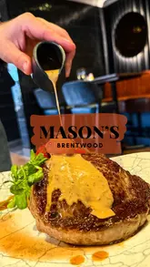 A promotional reel for Mason's in Brentwood, featuring a montage of cocktails, various plated dishes including scallops, prawns, beef pappardelle, ribeye steak, and desserts, set against the backdrop of the restaurant's interior.