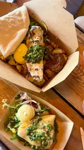 A short, montage-style video showcasing Riley's Fish Shack in Tynemouth. The video opens with a wide shot of the beachside location and the historic ruins in the background, followed by close-up shots of fresh seafood dishes, bread, and drinks on a wooden table.