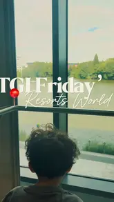 A short, family-oriented reel featuring a parent and child dining at TGI Fridays. The video captures the casual atmosphere, the view from the table, and close-ups of various menu items like wings, noodles, and a hot dog, highlighting the venue's suitability for family outings.