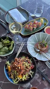 A visually appealing showcase of various dishes at a rooftop restaurant in London, featuring sushi, dim sum, and truffle risotto, set against a backdrop of city skyline views.