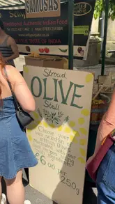 A creator visits the Suffolk Sunday Market in Cheltenham, walking through the stalls and highlighting various food vendors including a bakery, an Italian deli, an olive stall, and a Portuguese pastry stand.