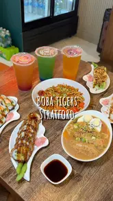 A short montage video showcasing various sushi rolls, ramen, udon noodles, and boba tea at the Boba Tigers Stratford location. The video features close-up shots of food being lifted with chopsticks, interior shots of the venue, and a brief look at the self-service ordering kiosk.