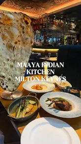 A creator visits Maaya Indian Kitchen & Bar in Milton Keynes, providing a review of their experience. The video features a variety of dishes including poppadoms, samosa chaat, Malabar scallops, paneer, lamb chops, sea bass, butter chicken, and desserts, alongside cocktails. The creator highlights the quality of the food and the friendly service.