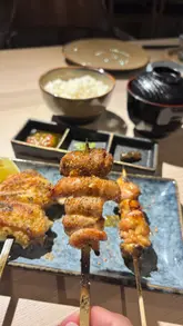 A high-quality, polished montage showcasing the interior and various dishes at Hotori, a Japanese restaurant in London, including yakitori, sushi, and desserts.