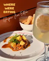 A close-up shot of a salmon tartare dish served with a cocktail in the foreground, taken in direct sunlight.