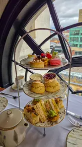 A short, aesthetic montage showcasing an afternoon tea service at The Rex Hotel in Manchester. The video features shots of the hotel exterior, the dining area with city views, and close-ups of the tea, scones, sandwiches, and pastries.