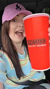 A couple visits a drive-thru burger spot called Kongz, showcasing the ordering process and the various takeaway items they purchased, including smash burgers, a doner pizza, a hot dog, and loaded fries.