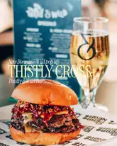A promotional image featuring a smash burger in the foreground with a glass of cider and a menu in the background, advertising a pop-up bar collaboration.