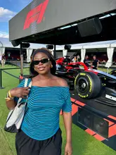 A photo of a creator posing in front of an F1 car at the Silverstone circuit during the British Grand Prix.