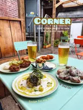 A top-down shot of a table filled with various small plates and two pints of beer in an outdoor courtyard setting.