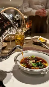 A montage of various fine dining dishes being finished with sauces poured tableside, highlighting the role of the saucier and the artistry of plating.