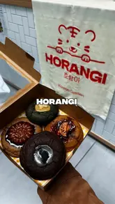 A short, engaging video showcasing Horangi Bake, an independent Korean home bakery in Manchester. The video features close-up shots of various handcrafted cookies, including black sesame and sweet potato cream cheese flavours, as well as a quick look at the storefront and branding. The content uses a voiceover to explain the concept and highlights the limited availability of the products.