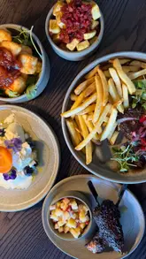 A montage showcasing the interior, drinks, and small plates menu at Brooks Deli & Wine Bar, featuring various dishes like steak frites, halloumi, and cocktails.