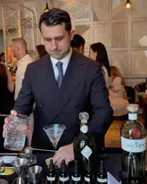 A high-quality, professional shot of a bartender preparing a cocktail at The Connaught Bar, capturing the sophisticated and refined atmosphere of the venue.