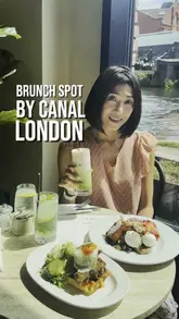 A short, aesthetic montage showcasing a brunch venue located by a canal. The video features close-up shots of plated dishes like fried chicken and waffles and an Italian breakfast, alongside refreshing drinks, interspersed with clips of the interior and the scenic waterside view.