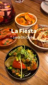The video provides a tour of La Fiesta, highlighting its Mediterranean-inspired small plates and buffet-style 'farmers market' table. It features a variety of dishes including salads, dips, cured meats, calamari, and meatballs, concluding with a dessert service.