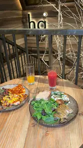 A vlog-style review of Honest Greens in London, highlighting the healthy menu, fresh juices, halal chicken options, and the restaurant's aesthetic which feels like a holiday destination.
