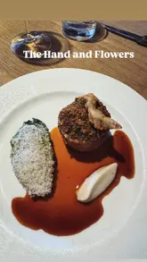 A review of The Hand & Flowers in Marlow, featuring a drive to the venue, a look at the lunch set menu, and close-ups of various dishes including sourdough, a tomato tart, chicken ballottine, and dessert.