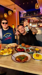 A group of friends visits an Indian restaurant, showcasing the indoor/outdoor seating, sizzling mixed grill, various curries, and dessert.