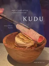 A dramatic, moody shot of a dessert being prepared or served with a glowing charcoal ember, showcasing the unique presentation style of the restaurant.