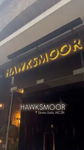 The video features a creator visiting a Hawksmoor restaurant to celebrate a 20th anniversary. It includes shots of the exterior, the interior atmosphere, a variety of cocktails, the menu, and several dishes including steak, sides, and desserts. The creator provides commentary throughout the experience.