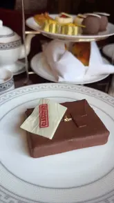 A short, aesthetic video showcasing a themed 'Operation Mincemeat' afternoon tea at Raffles London. The video features close-up shots of intricate, spy-themed pastries and sandwiches, set against the backdrop of an elegant hotel dining room.