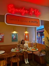 A lifestyle shot featuring a customer at a Miffy-themed afternoon tea at Cutter & Squidge. The image captures the branding and the experience but lacks focus on the food itself.