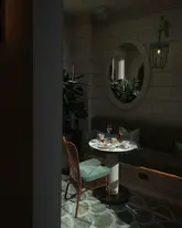 A moody, atmospheric shot of an afternoon tea service at Aki London, featuring a table set with various Japanese-inspired pastries and sandwiches. The lighting is dramatic and intimate, highlighting the elegant presentation of the food against a dark, sophisticated interior.