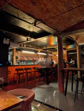 A moody, atmospheric shot of a basement bar interior, capturing the warm lighting and industrial brick architecture. The image effectively conveys a sophisticated, intimate vibe suitable for evening drinks.