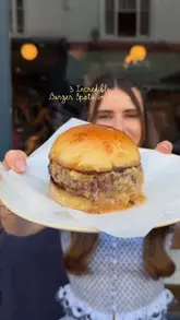 The creator presents a list of three recommended burger spots in London, providing brief commentary on each. The video features close-up shots of the burgers, including cutting into them to show the texture, as well as shots of the creator eating and the venue interiors.