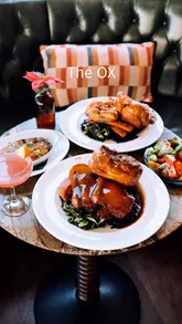 A short, visually appealing montage showcasing a Sunday roast experience at a pub called The Ox. The video features close-ups of the roast beef and pork belly, the preparation of a cocktail, and shots of the cozy interior, effectively highlighting the food and the relaxed atmosphere.
