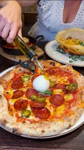 A high-energy review of an Italian restaurant in Sidcup, featuring a variety of dishes including pizza, pasta in a pizza bowl, wild boar ravioli, and pork ribs. The creators provide enthusiastic commentary on the food quality and presentation.